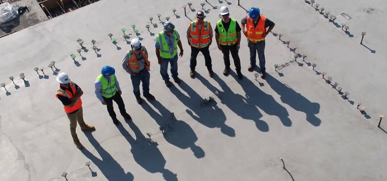 7 construction workers standing on a concrete slab